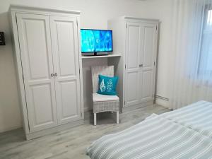 a bedroom with a bed and a tv and a chair at Huus Schippe "Stockholm" in Maasholm-Bad