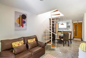 a living room with a couch and a spiral staircase at Apartamento a 500 m da Praia de Itacoatiara in Niterói