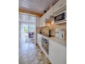 a kitchen with white cabinets and a tile floor at Holiday apartment sunrise in Dänschendorf