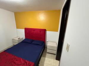 Un pequeño dormitorio con una cama roja y azul en Hostel Bogotá Normandia VIP, en Bogotá