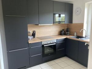 uma cozinha com armários pretos e um lavatório em Holiday house house sound of the sea em Borkum