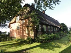 an old brick house on a green lawn at Romantic thatched roof house in Schnarup-Thumby