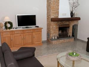 ein Wohnzimmer mit einem TV und einem Kamin in der Unterkunft Casa Schalkenmehren Grande in Schalkenmehren