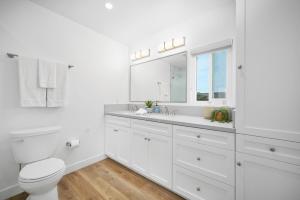 a white bathroom with a toilet and a sink at Remodeled - Modern - 2 Bedroom - Walk to the Beach in Newport Beach +23 photos