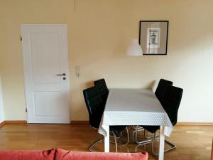 mesa de comedor con sillas negras y mantel blanco en Holiday apartment wind force 8, en Langeoog