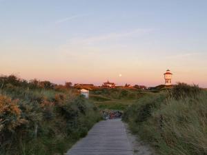 un chemin menant à un phare sur une colline dans l'établissement Holiday apartment wind force 8, à Langeoog