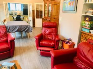 een woonkamer met rode stoelen en een tafel bij Maison avec piscine à Névez in Névez