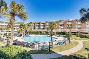 an apartment complex with a swimming pool and palm trees at Balcony and Gulf Views Galveston Condo Near Beach in Galveston