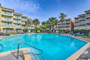 - une piscine dans un complexe avec des palmiers dans l'établissement Galveston Condo with Large Balcony Walk to Beach!, à Galveston