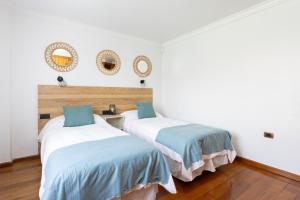 two beds in a room with white walls and wood floors at Casa Lali Habitación 2 in Las Lagunas