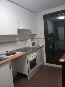 een keuken met witte kasten en een fornuis met oven bij C.Grafito 22 in Torrejón de Ardoz