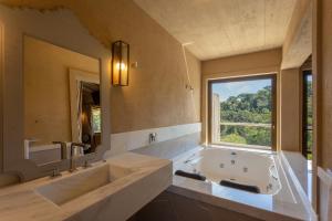 baño grande con bañera grande y ventana en Quinta dos Manacás Pousada - Pedra Azul - Rota dos Lagos en Pedra Azul