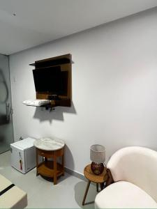 a living room with a chair and a tv on a wall at Hotel Villa Babaçu in Jacobina