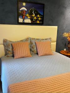 uma cama com almofadas laranja e uma fotografia na parede em Hotel Villa Babaçu em Jacobina