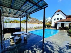 uma piscina com uma pérgula ao lado de uma casa em Villa Sampaguita 4bedroom Private Villa em Kampong Alor Gajah