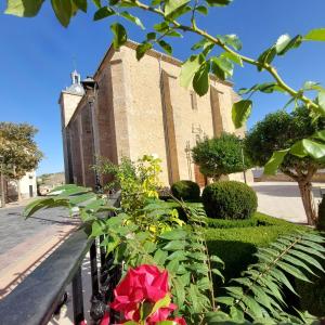 eine Kirche mit einem Zaun und Blumen davor in der Unterkunft Casa Rural Rincones de Albares in Albares