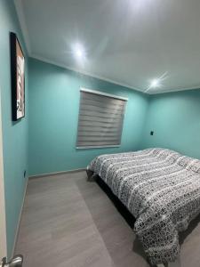 um quarto com uma cama e uma parede azul em Casa en pichilemu em Pichilemu