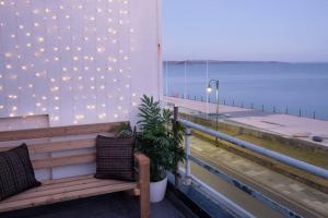 a bench on a balcony with a view of the ocean at Stunning seaside penthouse apartment with balcony in Newlyn