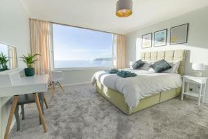 a bedroom with a bed and a desk and a window at Stunning seaside penthouse apartment with balcony in Newlyn