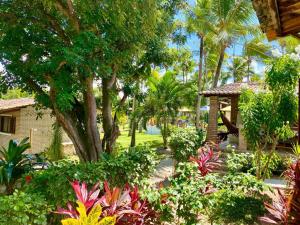 un jardin avec des plantes et des arbres et une maison dans l'établissement Chalé Centro, Praia Pipa, à Pipa