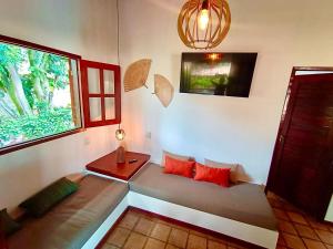 um quarto com um sofá com almofadas vermelhas e uma janela em Chalé Centro, Praia Pipa em Pipa