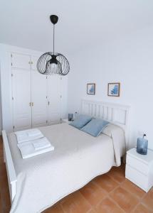 a bedroom with a white bed and a chandelier at Apartamento Atardeceres in Ayamonte