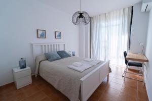 a white bedroom with a bed with towels on it at Apartamento Atardeceres in Ayamonte