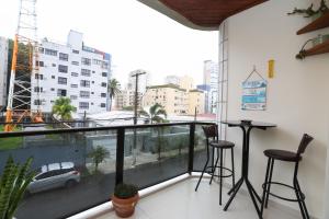 uma varanda com dois bancos de bar e vista para a cidade em Apartamento Praia do Tombo Guarujá 120m do mar no Guarujá