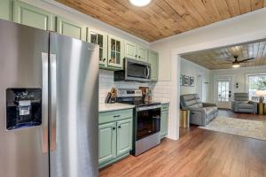 a kitchen with green cabinets and a stainless steel refrigerator at Modern-Boho Bradenton Bungalow with Private Hot Tub! in Bradenton
