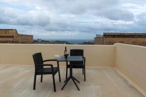 a table and chairs on a balcony with a bottle of wine at Casa Maria Pia in Nadur