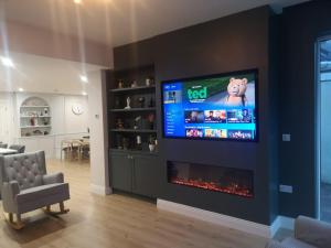 een woonkamer met een open haard en een flatscreen-tv bij The Happy Heron in Donegal