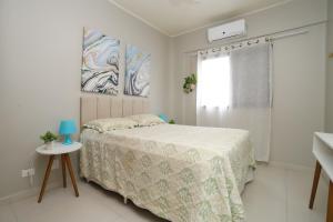 um quarto branco com uma cama e uma janela em Apartamento Praia do Tombo Guarujá 120m do mar no Guarujá