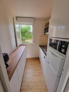 a small kitchen with white appliances and a window at Villa Soustons Plage / Résidence les villas du lac avec piscine in Soustons