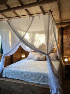 een slaapkamer met een hemelbed met klamboes bij Chalé encantado Ambika eco Arraial d Ajuda in Porto Seguro