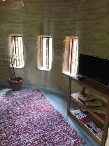 een woonkamer met een flatscreen-tv en 3 ramen bij Chalé encantado Ambika eco Arraial d Ajuda in Porto Seguro