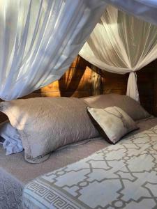 een bed met een baldakijn en twee kussens erop bij Chalé encantado Ambika eco Arraial d Ajuda in Porto Seguro