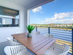 d'une table en bois et de chaises blanches sur un balcon. dans l'établissement Gorgeous 2BR lakeview Condo with Waterpark, à Kissimmee