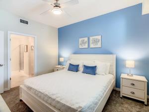 - une chambre avec un grand lit blanc aux murs bleus dans l'établissement Gorgeous 2BR lakeview Condo with Waterpark, à Kissimmee