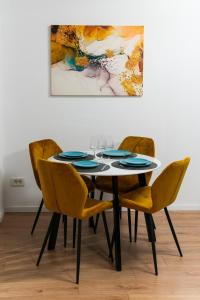een eettafel met gele stoelen en een schilderij bij Sandra in Boekarest