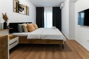 een slaapkamer met een bed met witte muren en houten vloeren bij Sandra in Boekarest