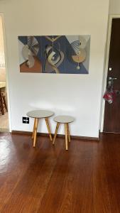 two tables in front of a white wall at Apartamento Centro ao lado do Country Club in Nova Friburgo