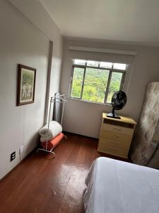 a bedroom with a bed and a window and a dresser at Apartamento Centro ao lado do Country Club in Nova Friburgo