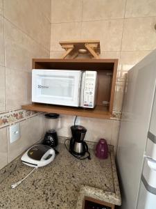 a microwave on a shelf above a kitchen counter at Apartamento Centro ao lado do Country Club in Nova Friburgo