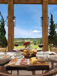 a wooden table with food and wine glasses on it at Quinta dos Manacás Pousada e Restaurante in Pedra Azul
