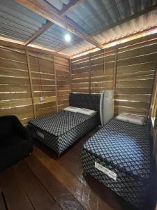 a room with two beds in a room with wooden walls at Cabana tucuxi in Novo Airão