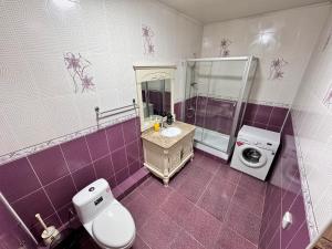 een badkamer met een toilet, een wastafel en een wasmachine bij Poytakht 80 Apartments in Doesjanbe