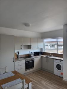 a kitchen with white cabinets and a sink and a table at Mountain View Cottages V92X961 in Tralee