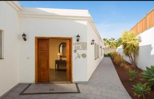 a white house with a wooden door and a walkway at Villa Pipa Puerto Calero in Puerto Calero