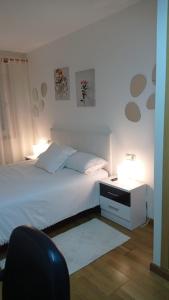 um quarto com uma cama branca e 2 candeeiros em Casa Preguntoiro em Vilagarcía de Arousa