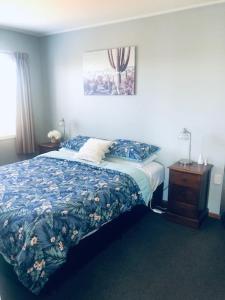 a bedroom with a bed with a blue comforter at Clyde Suite in Tauranga